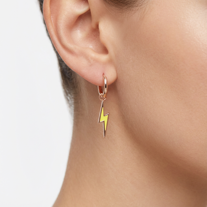 Earring with a yellow lightning bolt charm worn by a person on a white background