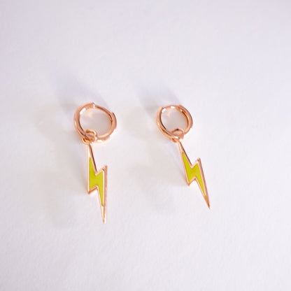 Rose gold earrings with green lightning bolt designs on a light gray background